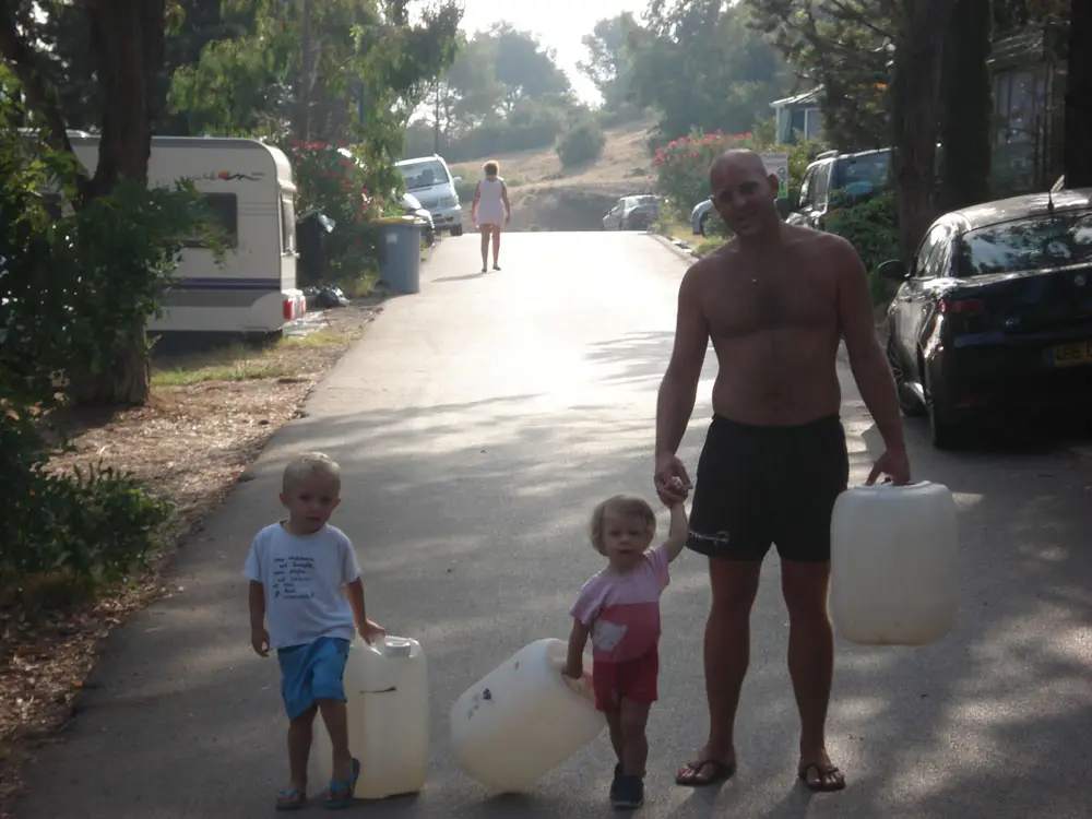 Vader en zijn twee kinderen op weg om de jerrycans te vullen op camping Esterel Caravaning