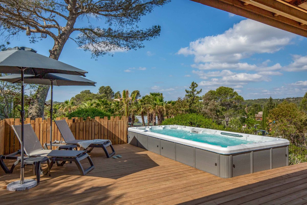 Privé zwemspa en ligstoelen op het houten terras van de VIP Duo op Esterel Caravaning, onder de pijnbomen